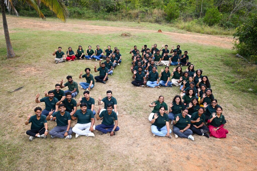 The Saahas team seated on a field forming the number 25